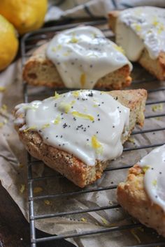 lemon poppy seed scones with white icing on a wire rack and some lemons in the background