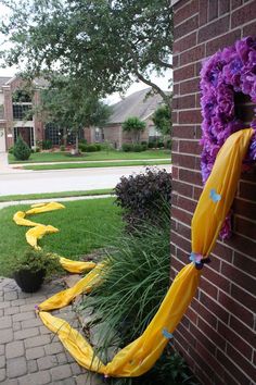 purple and yellow decorations on the side of a brick building in front of a house