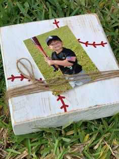 an old photo frame with a boy holding a baseball bat in it on the grass