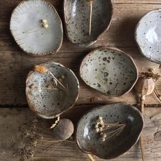 four ceramic bowls sitting on top of a wooden table next to dried flowers and herbs