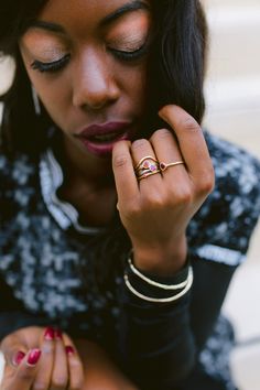 a woman is holding her hand up to her face and looking down at her ring