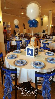 a table is set with blue and white plates, silverware, and balloons in the background