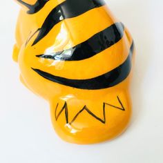 a yellow and black ceramic tiger head on a white surface