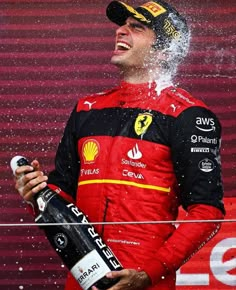 a man in a red and black suit is spraying water on his face