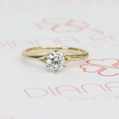 a yellow gold ring with a single diamond in it's center on top of a piece of paper