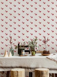 a table topped with two vases filled with flowers next to a wallpapered wall