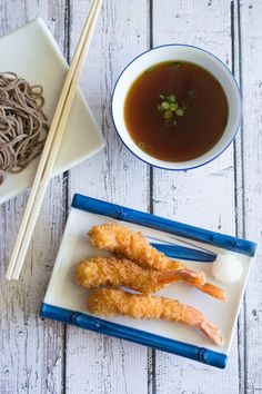 some food is sitting on a plate with chopsticks next to it and a bowl of soup