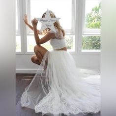 a woman kneeling down in front of a window wearing a white wedding dress and veil