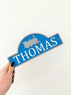 a person holding up a blue sign that says thomas