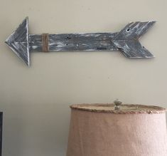 an arrow made out of wood is on the wall next to a lamp with a light shade