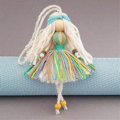 a doll with long white hair wearing a colorful dress on top of a yoga mat