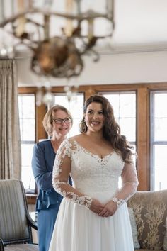 a woman in a wedding dress standing next to another woman with glasses on her head