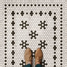 a person standing on a tiled floor with their feet up in the air and wearing brown shoes