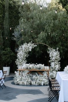 an outdoor wedding setup with white flowers and candles