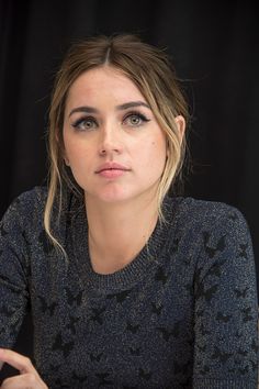 a woman sitting at a table with a laptop in front of her and looking off to the side