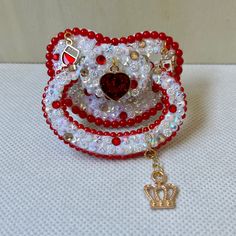 a red and white beaded bracelet with a crown charm on it's end