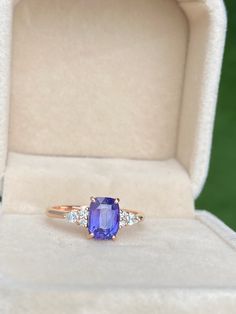 a tan gold ring with an oval blue stone surrounded by three white diamonds in a box