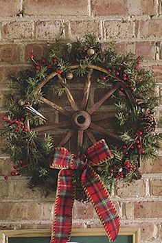 a christmas wreath hanging on the side of a brick wall with a chalkboard underneath it