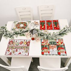 a white table with christmas decorations and candles on it, along with two matching placemats