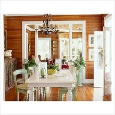 a dining room table and chairs in front of a doorway with wood paneled walls