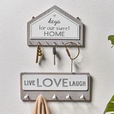 a coat rack with hooks and keys hanging on it's side next to a sign that says live love laugh