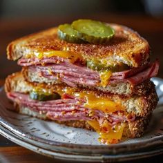 a grilled cheese sandwich with pickles and mustard on a white plate sitting on a wooden table