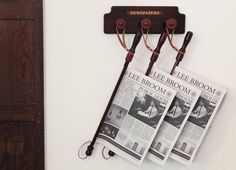 there are three newspaper racks on the wall with umbrellas attached to them, and one is holding two newspapers