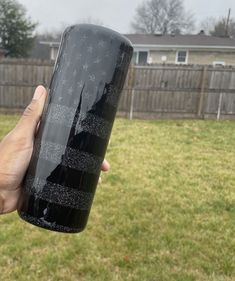 a person holding up a large black cup in their hand with snowflakes on it