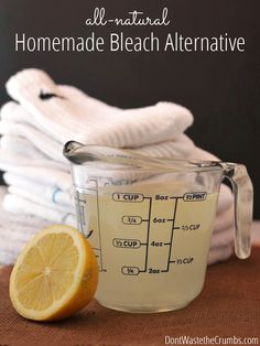 a glass measuring cup filled with liquid next to a pile of folded towels and a lemon