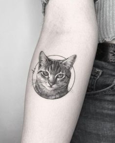 a black and white photo of a cat's face in a circle tattoo on the arm