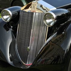 the front end of an old fashioned car with chrome grills and lights on it