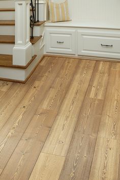 a wooden floor with white cabinets and stairs