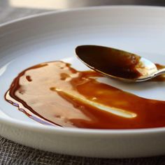 a spoon sitting on top of a white plate covered in caramel sauce