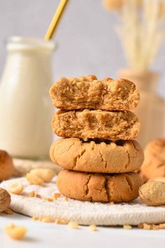 three cookies stacked on top of each other with nuts around them and a glass of milk in the background