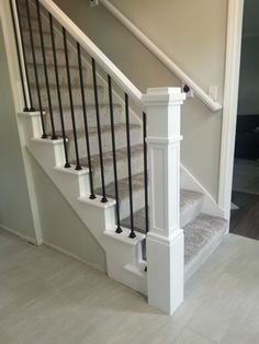 a white staircase with black handrails and carpeted steps in a home's entryway