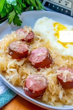 a white plate topped with mashed potatoes and sausage on top of sauerkraut