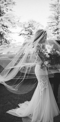 black and white photo of a bride with her veil blowing in the wind