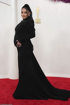 the pregnant woman is posing on the red carpet