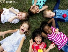 several children laying on the grass with their hands in the air and smiling at the camera