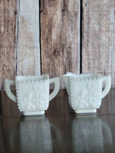 two white cups sitting on top of a wooden table