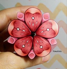 a close up of a person holding a flower brooch in their hand with hearts on it