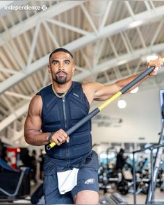 a man holding a pole in the middle of a gym