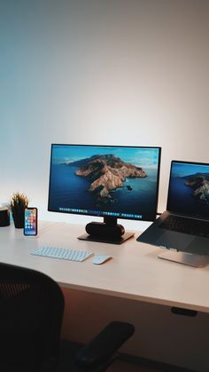 two computer monitors sitting on top of a white desk