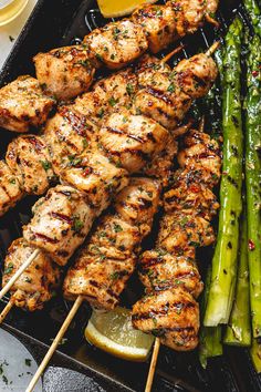 chicken and asparagus skewers on a grill with lemon wedges in the foreground