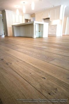 an empty living room with wood floors and white cabinets