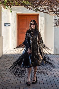 Designed to evoke the beauty and mystery of all things shimmery, this piece is crafted with a semi-sheer, dark black sequined mesh complimented in design by a mock neck, keyhole cutout at back, matching slip, and a striking black knotted silk fringe. Effortless ballroom elegance in a timeless silhouette. Our caftan dresses are a voluminous fusion of comfort, elegance, and daring expression. The intention of this shape is to celebrate the magic of fabric and its captivating dance with form - an e Luxury Black Kaftan For Party, Luxury Traditional Sequin Kaftan, Black Embellished Wedding Kaftan, Luxury Designer Sequined Kaftan, Luxury Sequined Maxi Kaftan, Black Floor-length Evening Kaftan, Bohemian Black Floor-length Kaftan, Caftan Dresses, Luxury V-neck Sequined Kaftan