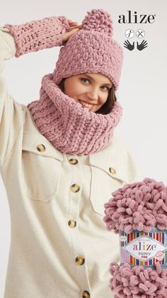 a woman wearing a pink knitted hat and scarf with buttons on the side, while holding her hands behind her head