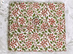 a red and green placemat with holly leaves on it, sitting on a marble surface