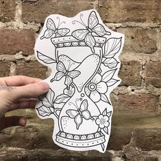 a hand holding up a sticker with an image of a vase and butterflies on it