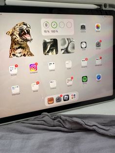 an ipad with icons on the screen is sitting on a bed next to a gray blanket